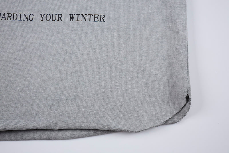 Close-up of a gray distressed sleeveless T-shirt hem with raw edge and partial black text print