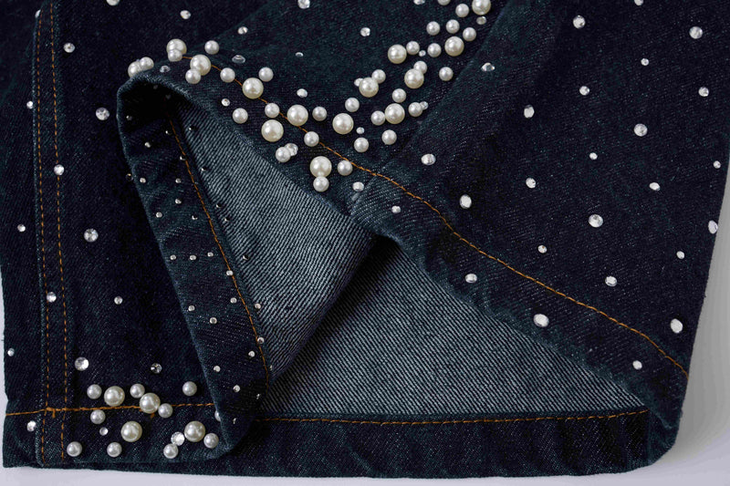 Close-up of folded black denim shorts with pearl stud detail