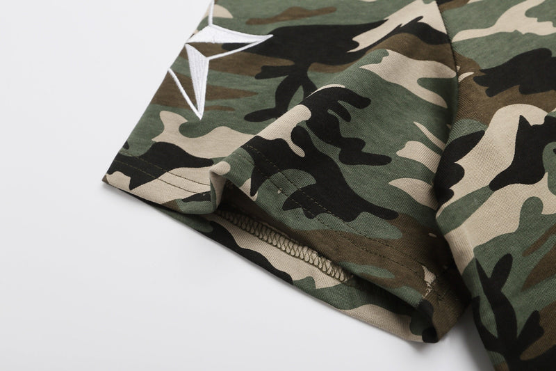 Close-up of a camo polo shirt hem with embroidered white logo on green, tan, and black camouflage fabric