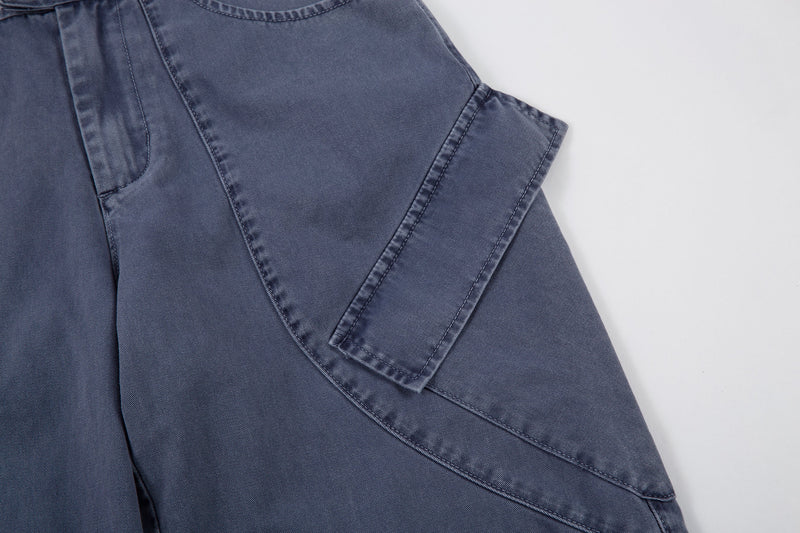 Side detail of blue denim pants showing wide leg and curved cargo-style seam
