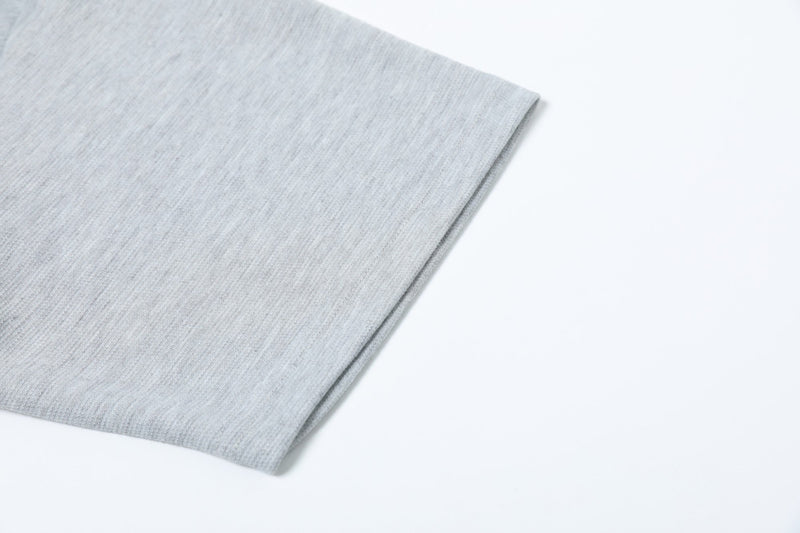 Light gray textured polo shirt sleeve with subtle embroidered detailing on a clean white background