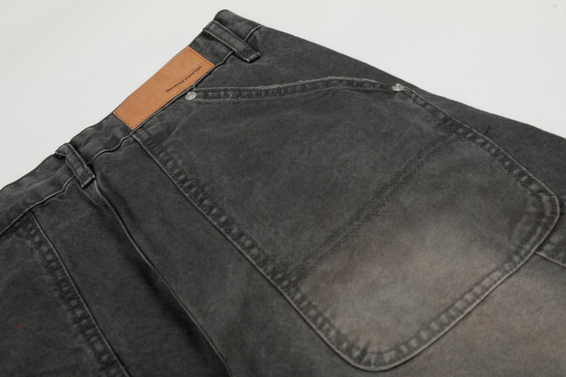 Close-up of the back waistband label and rear pocket seam on washed black denim pants
