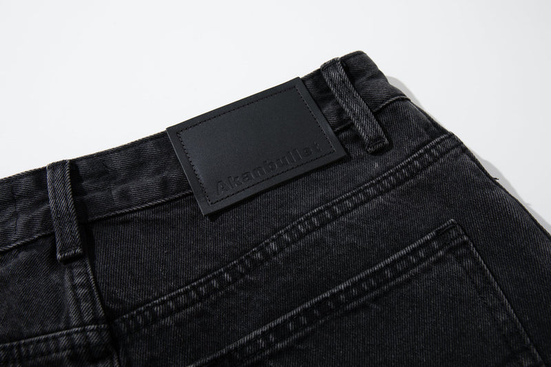 Close-up of the back waistband and leather patch on washed black denim