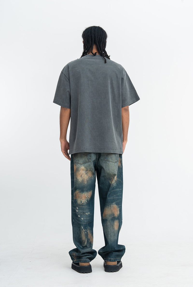 Back view of a vintage-wash charcoal graphic T-shirt paired with distressed wide-leg jeans and black boots