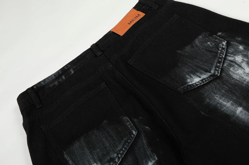 Back pocket close-up on black jeans with orange MEIM patch at the waistband