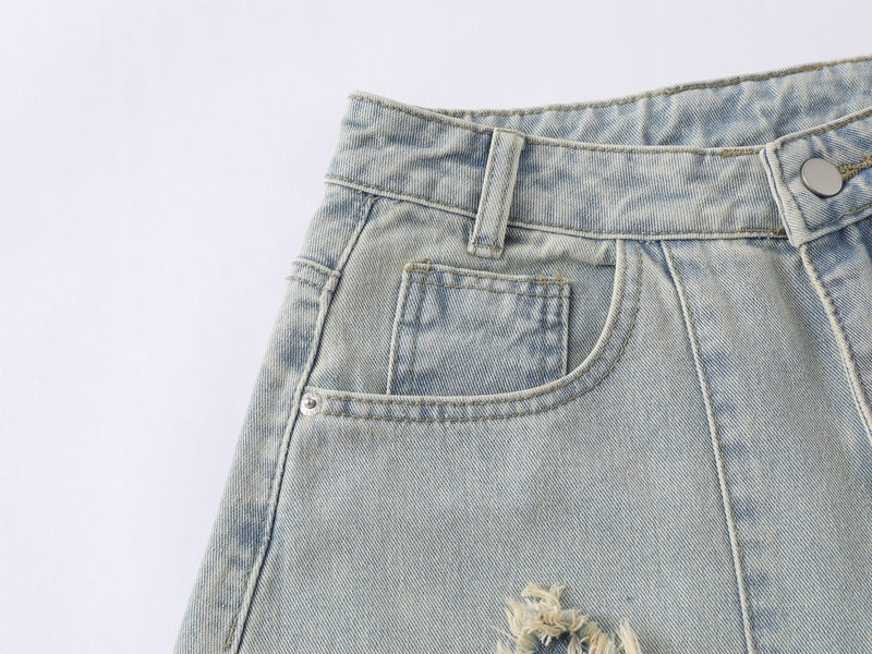 Close-up of the front pocket, waistband, and button on faded blue denim jeans