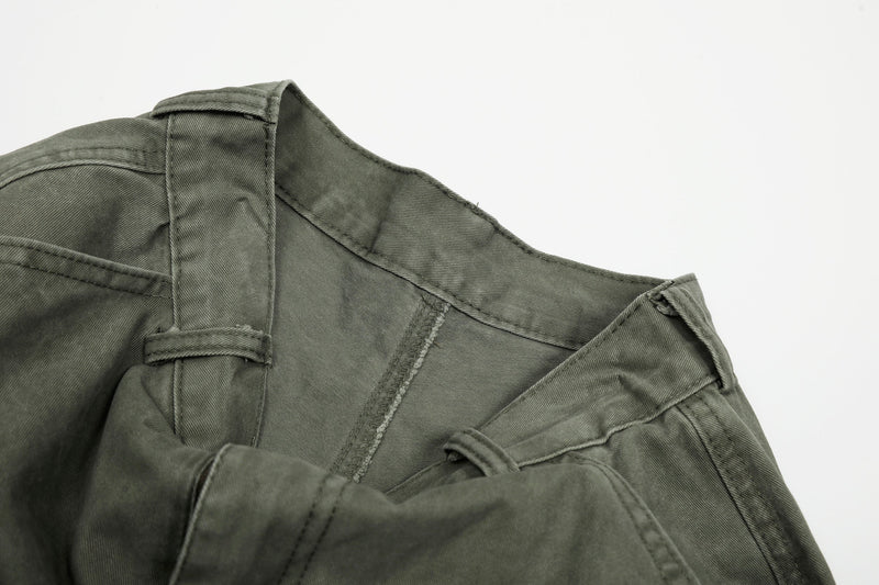 Close-up of olive green pants waistband and curved seam near the hip