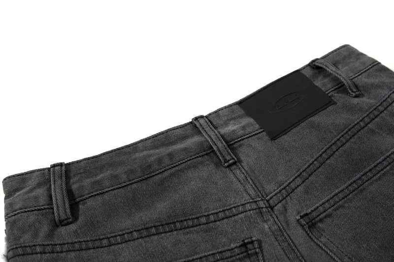 Close-up of back waistband with black patch label on washed black denim