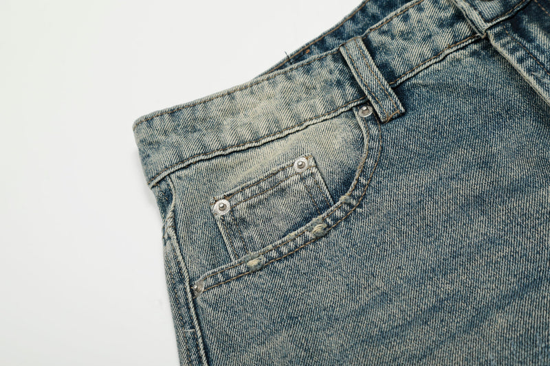 Close-up of front pocket and waistband on faded blue jeans with visible fading and worn stitching