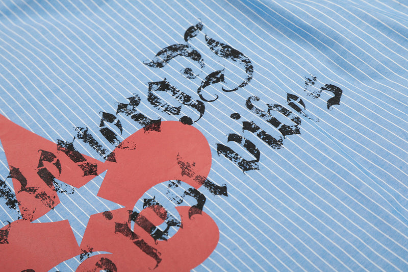 Close-up of red and black text graphic on blue striped shirt fabric