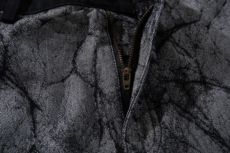 Close-up of front zipper on gray cracked-texture denim pants