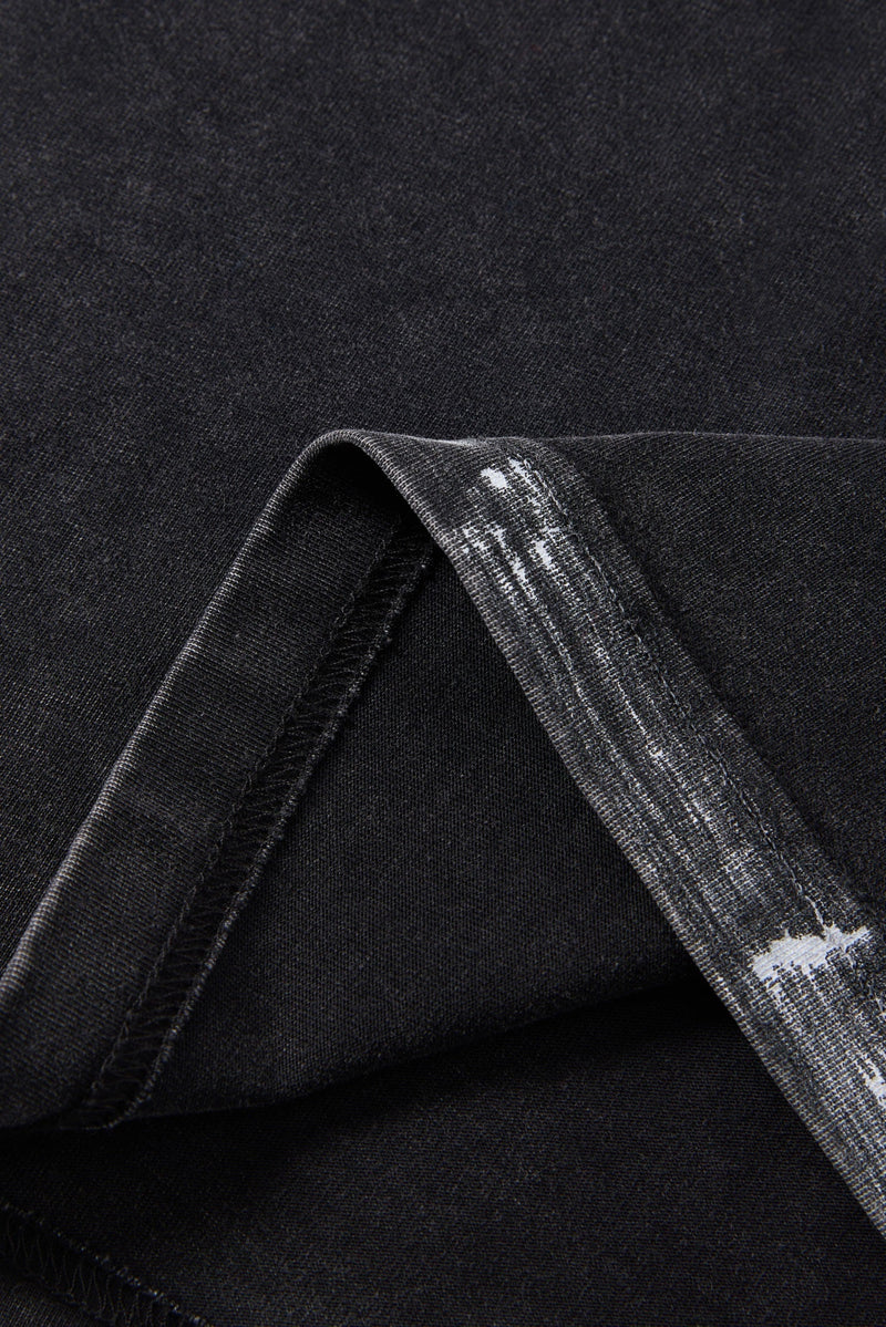 Close-up of black washed cotton T-shirt fabric with visible hem stitching and folded sleeve detail
