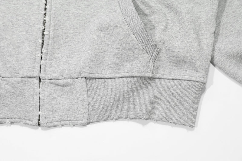 Close-up of light gray hoodie front hem, pocket edge, and ribbed waistband