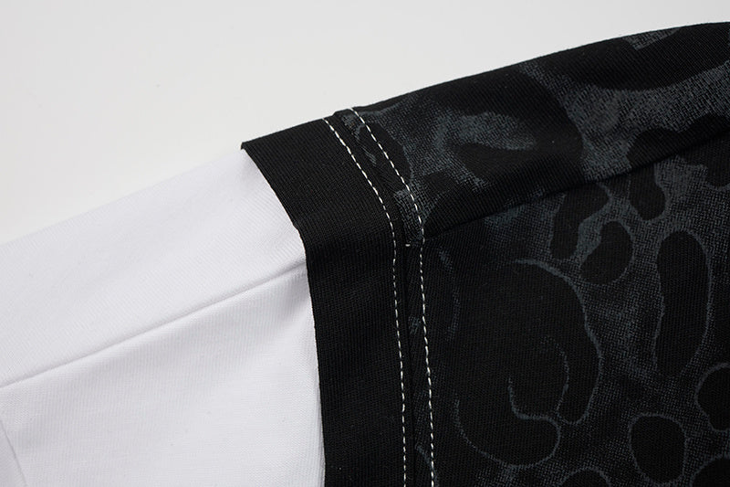 Close-up of black mesh leopard print overlay with white sleeve and visible contrast stitching on a layered graphic T-shirt