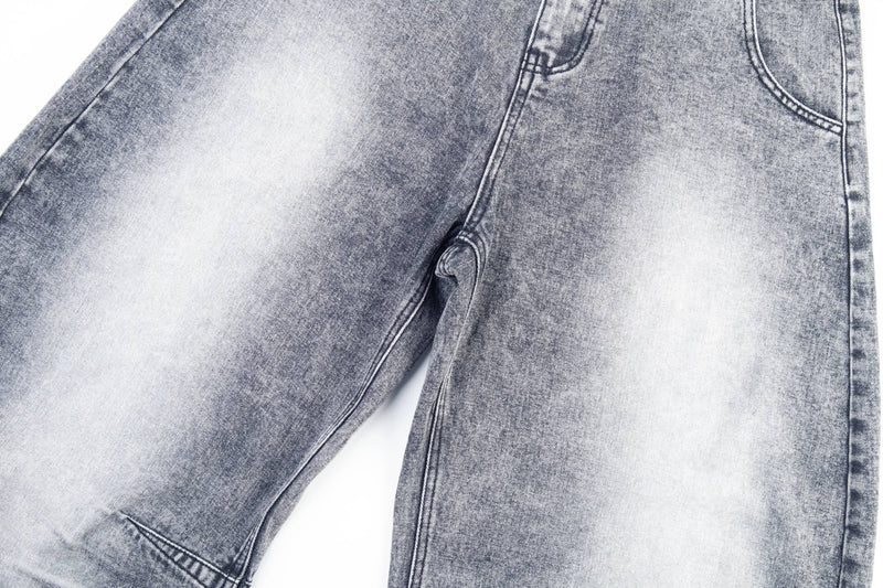 Close-up of gray denim leg with faded wash and a torn knee detail