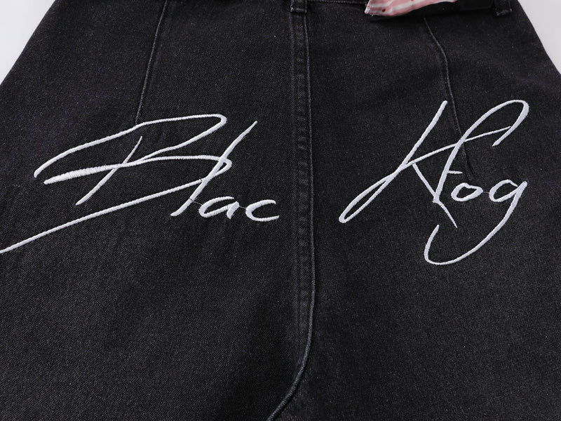 Close-up of white script embroidery on black denim back