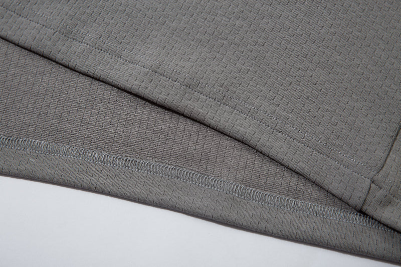 Close-up of gray hem stitching and layered mesh fabric on the polo shirt
