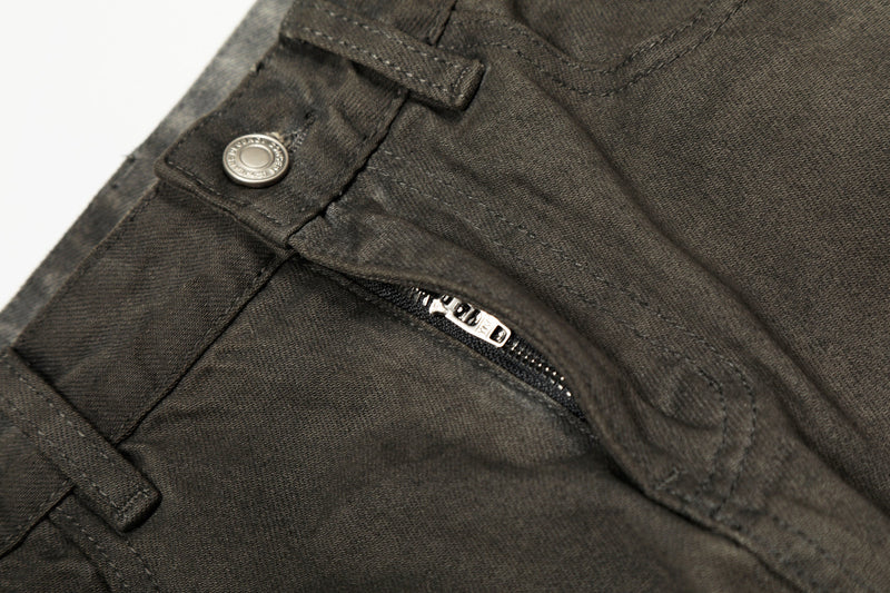 Close-up of front fly zipper and waistband on faded black denim pants