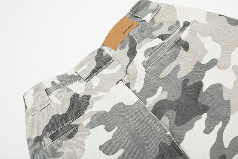 Close-up of camo cargo pants waistband with tan patch, belt loop, and top pocket seam