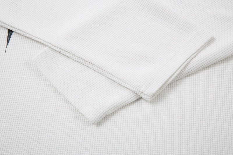 Folded white long sleeve tee showing textured waffle knit fabric and cuff seams
