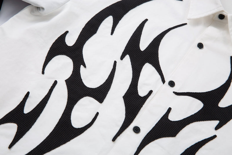 Diagonal close-up of black flame print across white button-up shirt front