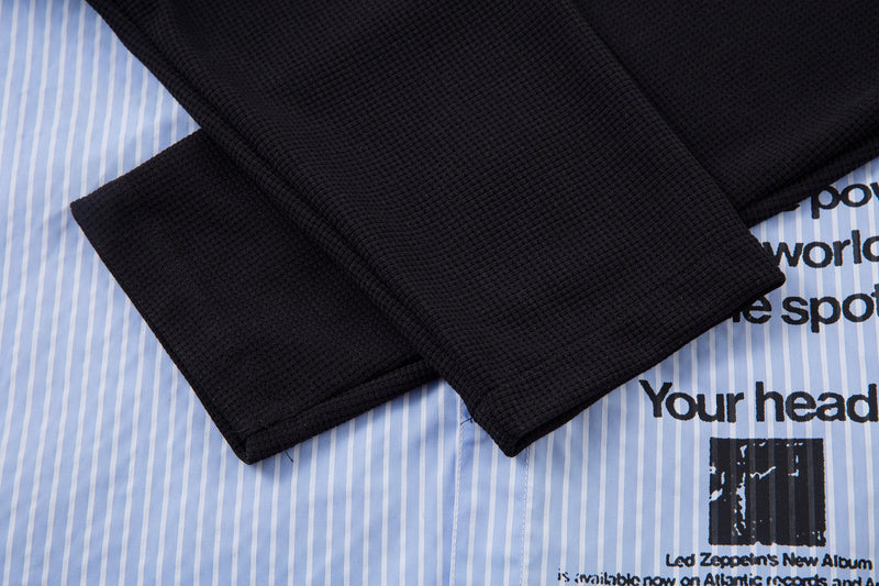 Black textured sleeves draped over the light blue pinstripe shirt front
