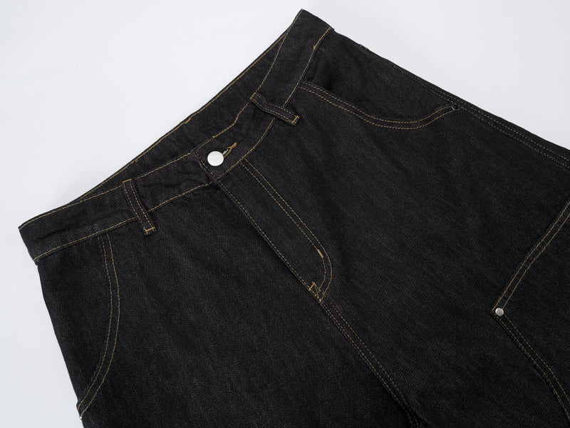 Close-up of dark wash denim waistband with metal button, belt loops, and contrast stitching