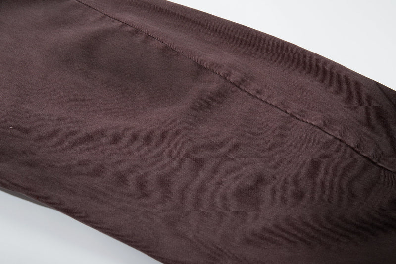 Close-up of brown denim leg fabric with visible seam and diagonal wash