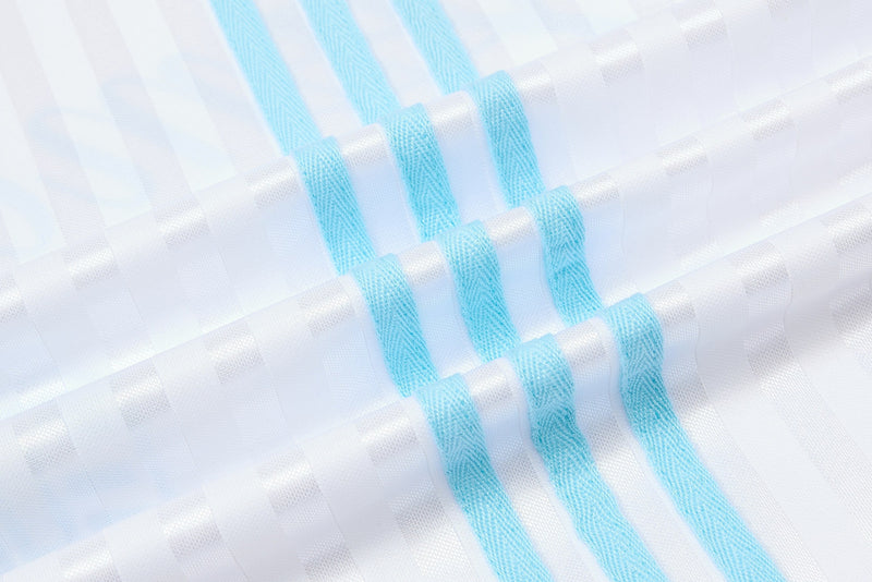 Close-up of a white football jersey with light blue script stripes and textured retro streetwear fabric