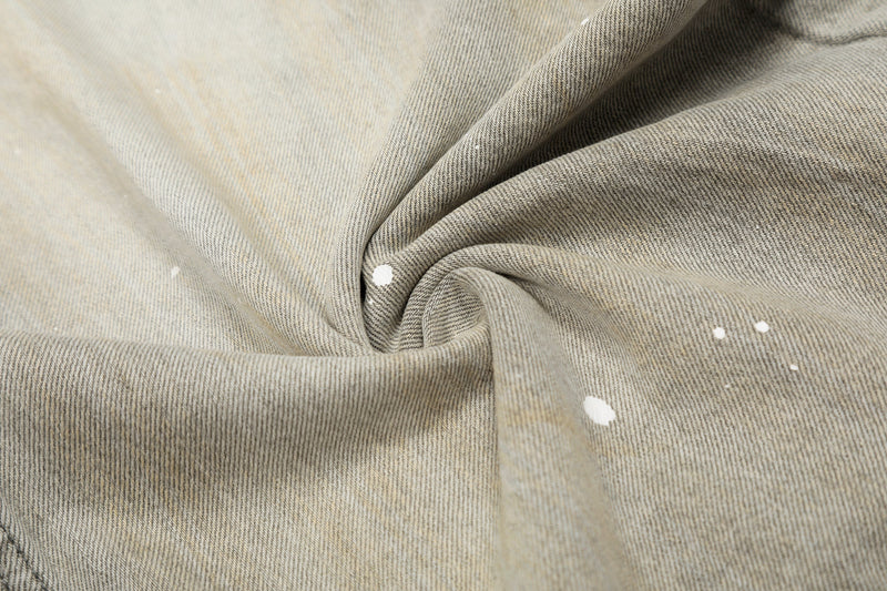 Close-up of gray denim fabric with white paint splatter and soft fold