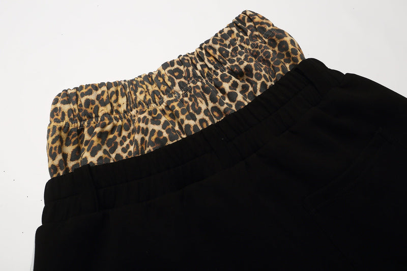 Close-up of gathered leopard waistband above the black shorts body