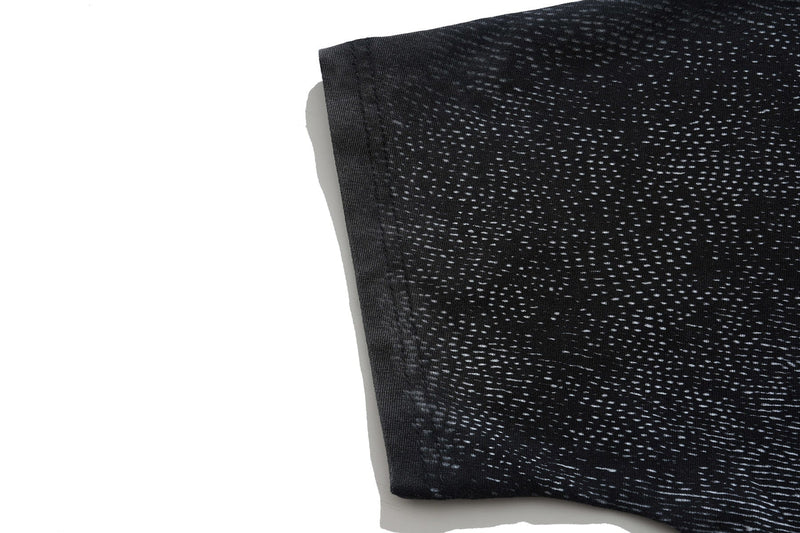 Close-up of black vintage washed tee sleeve with distressed white graphic print and raw hem detail