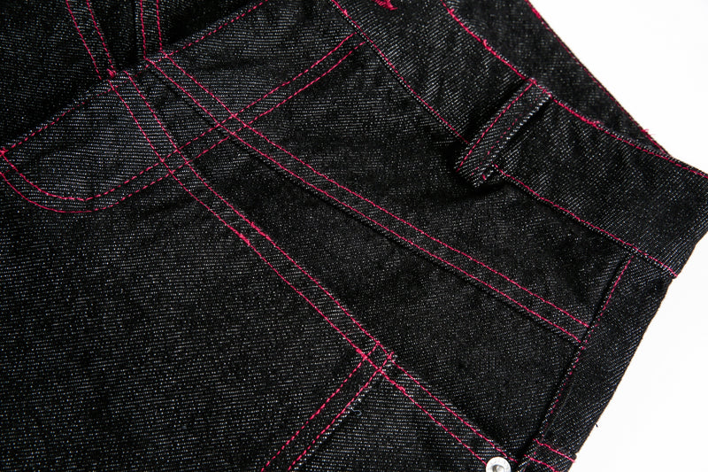 Close-up of black denim pocket seam with red contrast stitching
