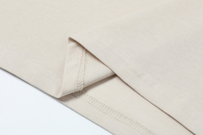 Close-up of cream deconstructed collar tee with clean stitched seams and minimalist folded fabric detail