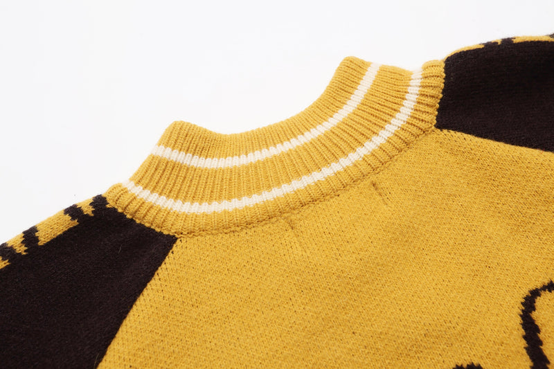 Close-up of yellow knit collar and shoulder detail with white trim and black sleeve