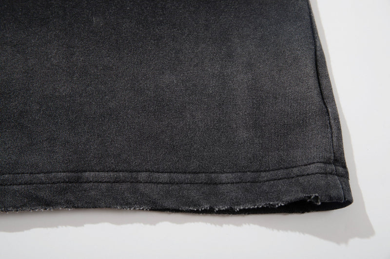 Close-up of a washed black graphic tee hem with raw distressed edging and visible stitching
