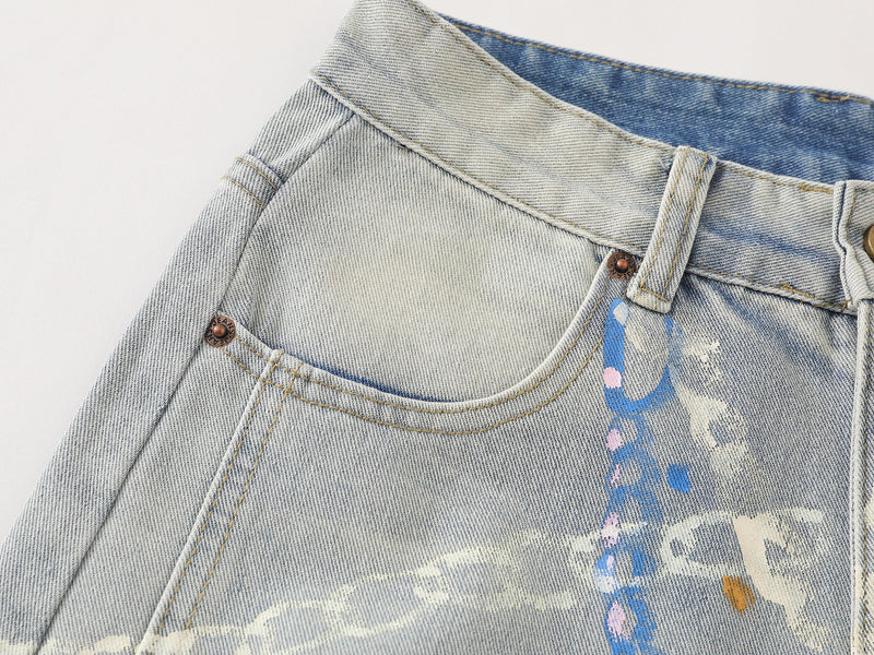 Close-up of front waistband and pocket on light wash denim pants with painted details