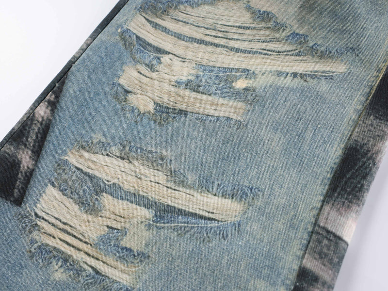 Close-up of distressed ripped patch on light blue denim jeans leg