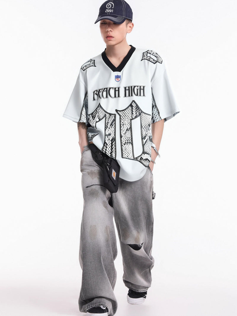 White oversized jersey tee with snakeskin print and black V-neck, styled with gray baggy jeans and cap
