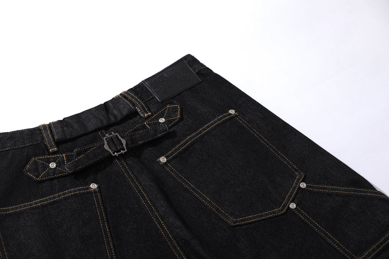 Close-up of black denim back pocket and waistband with buckle strap detail