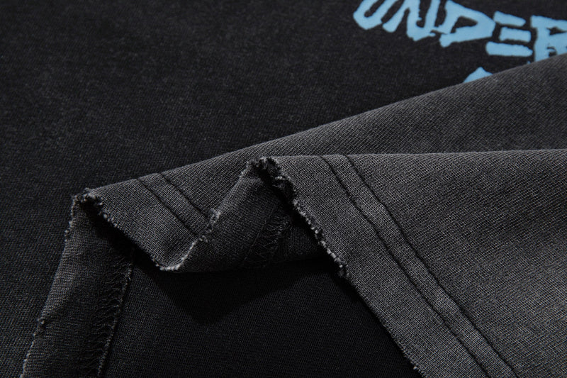 Black washed vintage graphic tee with frayed seams and light blue grunge lettering detail at the chest