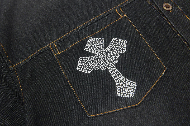 Black denim shirt pocket with rhinestone cross detail and contrast stitching, streetwear-style button-up close-up