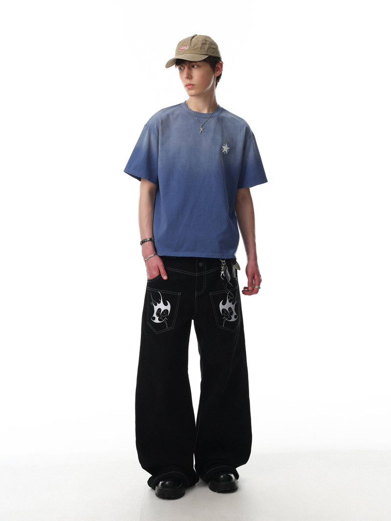 Blue gradient washed cotton tee with small star graphic on chest, styled on model with black wide-leg pants and cap