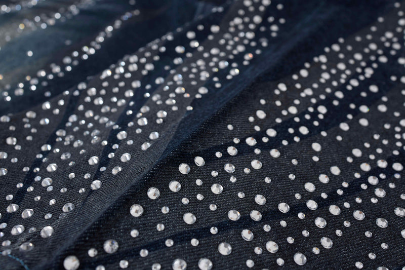 Close-up of rhinestones on dark wash denim fabric