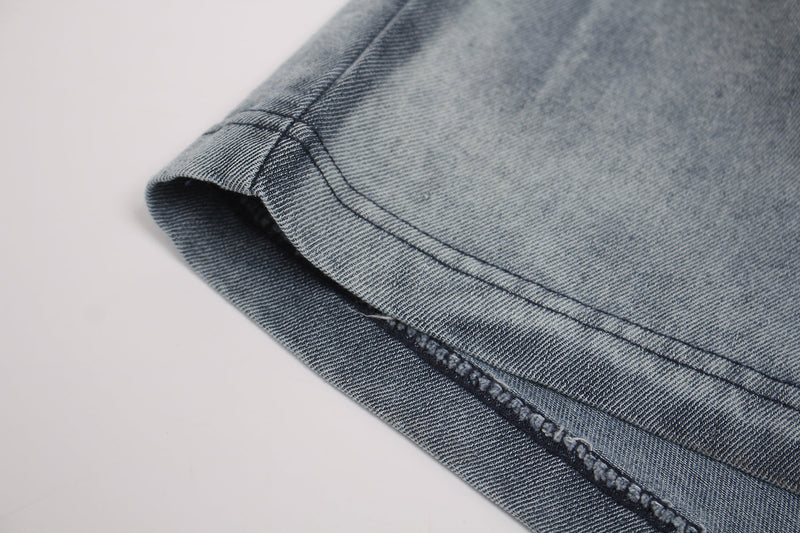 Close-up of a vintage washed blue distressed T-shirt sleeve with faded denim texture and visible stitched hem