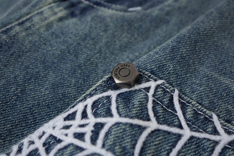 Close-up of light wash denim shorts spiderweb panel snap button on denim pocket