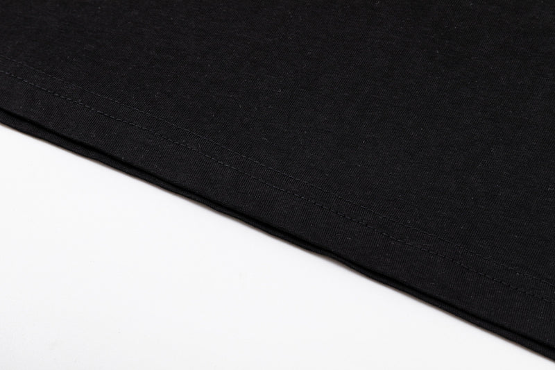 Close-up of black oversized graphic tee hem with neat double stitching on a clean white background