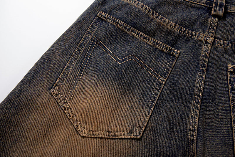 Close-up of a back patch pocket on faded dark-wash jeans with contrast stitching