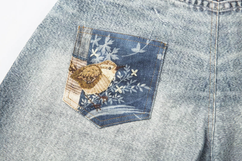 Back pocket close-up with bird patch on light wash denim shorts