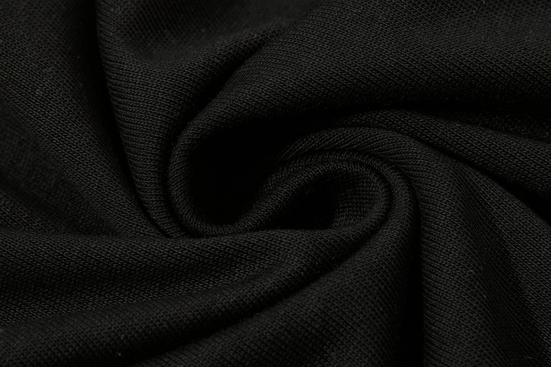 Close-up of black textured cotton polo fabric with soft folded drape and a streetwear-inspired finish